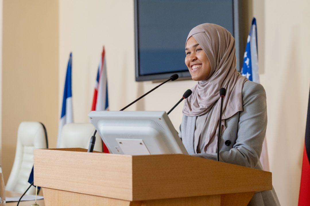 Young successful muslim businesswoman in hijab standing by tribune.jpg